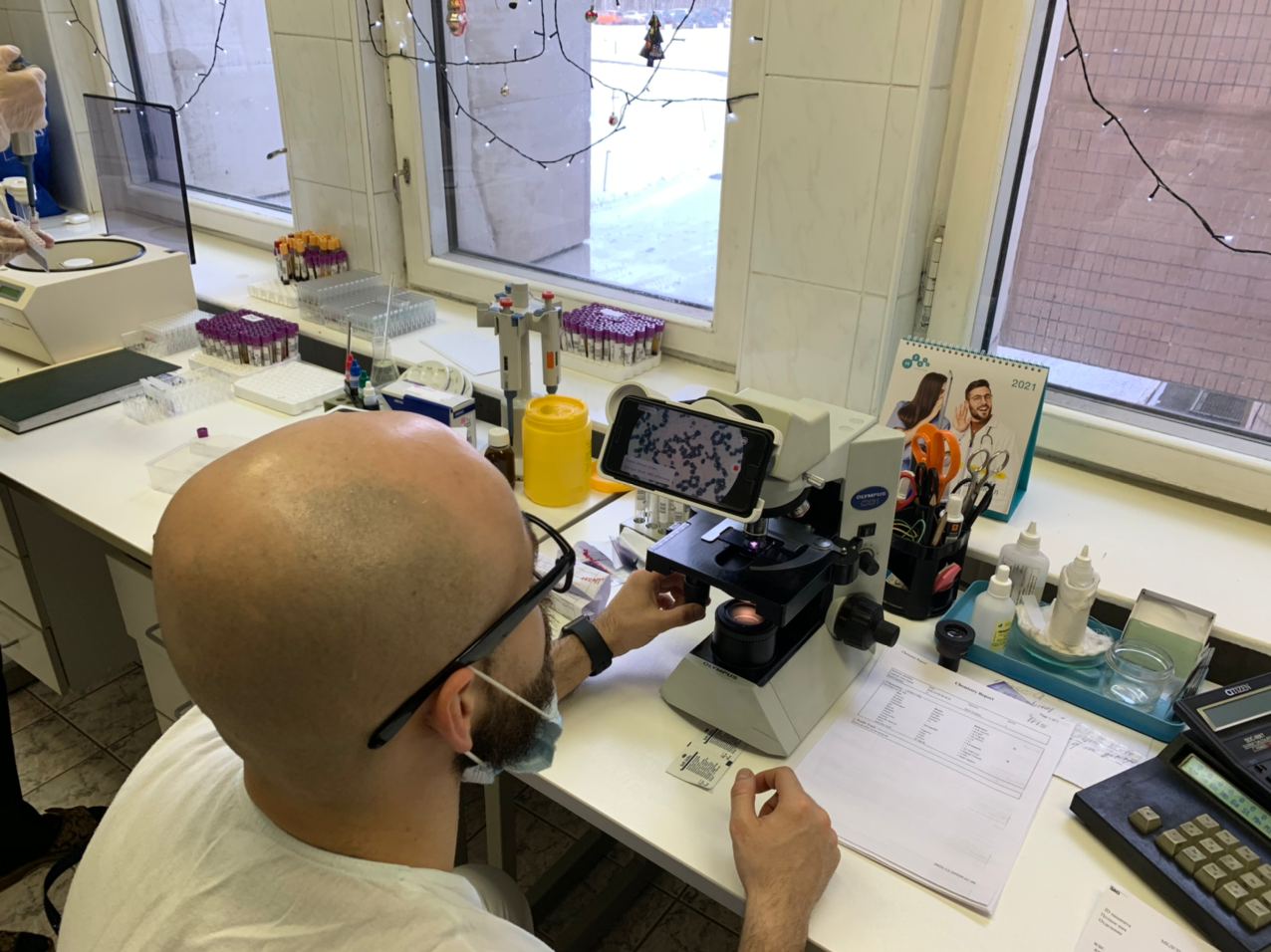 Врач проверяет мазок крови под микроскопом через iPhone