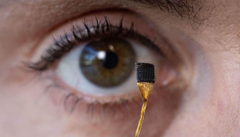 Соавтор исследования держит микроэлектродный массив, который после имплантации в кору мозга передает сигналы нейронной активности в компьютер. Источник