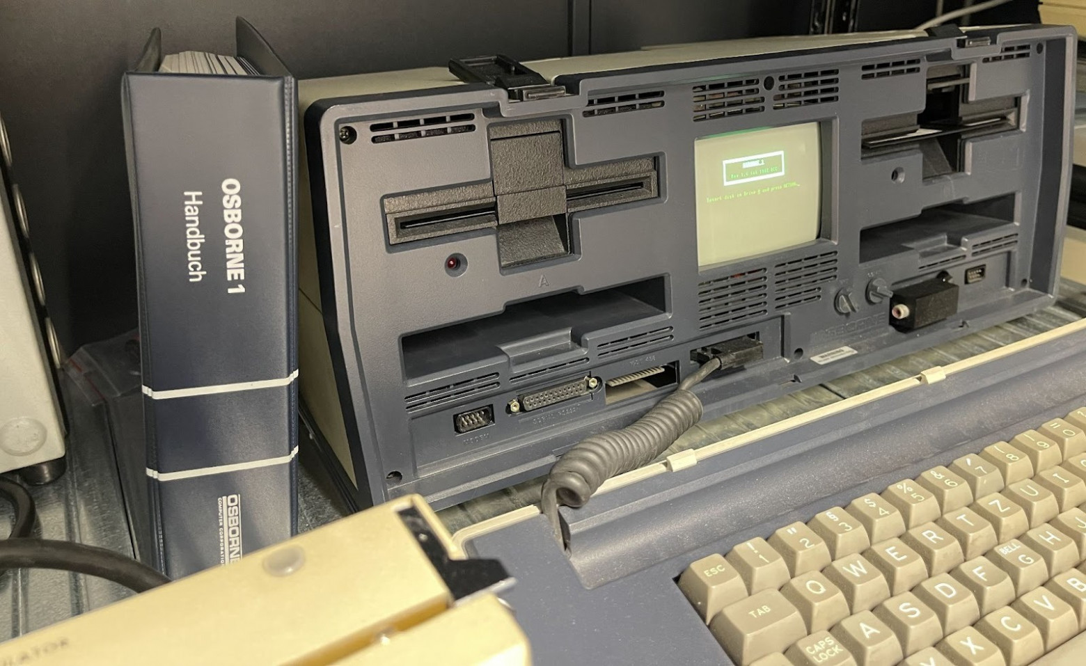 Снова фотографии из Университета Штутгарта. Слева потрясающая по качеству книжка мануала на немецком. В центре фотографии под дисководом темный прямоугольник – это стандартный карман для хранения дискет. Справа такой же карман