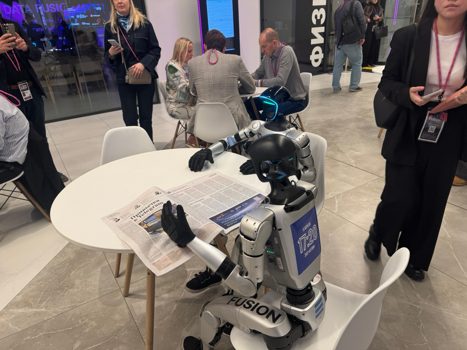 Роботы молча читают газету в сторонке